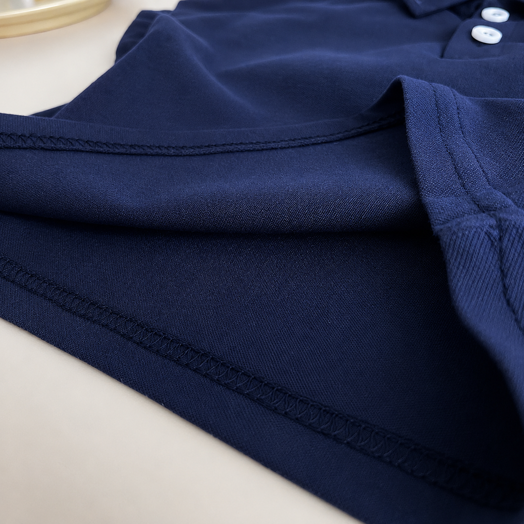 Gros plan sur le tissu bleu marine d’un polo bébé garçon montrant la qualité du textile, les coutures renforcées, les finitions soignées et le confort du vêtement pour une utilisation quotidienne.