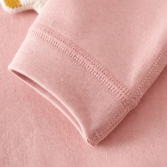 Gros plan sur la manche d’un pyjama pour bébé rose montrant le tissu doux et les coutures soignées au niveau du poignet.