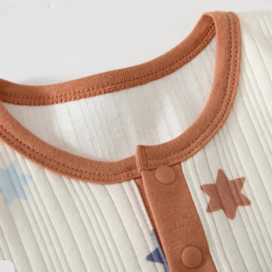 Zoom sur col barboteuse bébé en coton doux avec boutons pression et finition marron, vêtement nourrisson confortable manches longues.