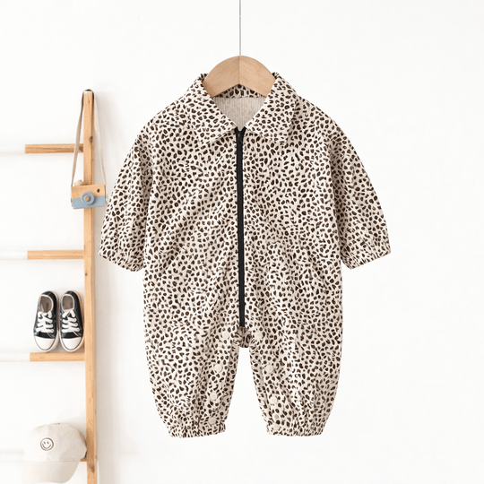 Barboteuse bébé beige motif léopard avec fermeture zippée et col chemise, combinaison confortable pour nourrisson suspendue sur cintre en bois.