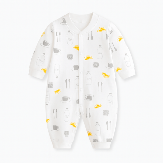 Combinaison bébé blanche décorée de motifs tasses, bouteilles de lait, cuillères et petits fruits jaunes, style gourmand et original.