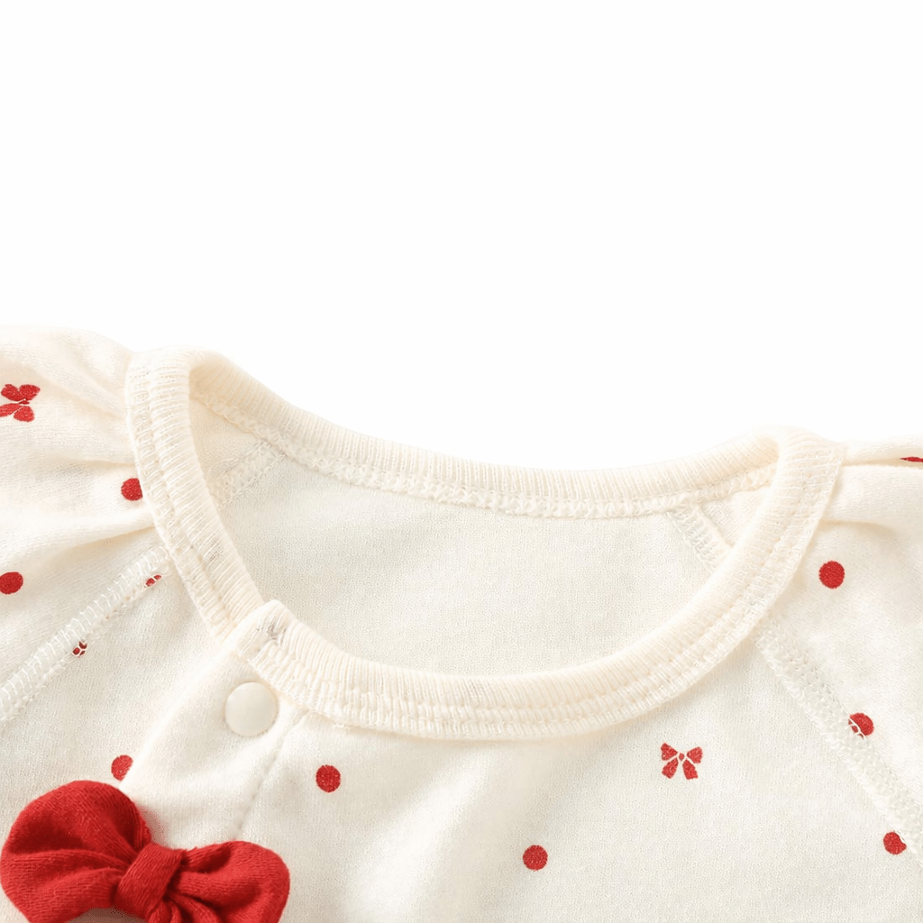 Zoom sur barboteuse bébé fille en coton doux avec col rond extensible et nœud rouge, motif pois rouges, combinaison confortable pour enfant 1 à 3 ans.