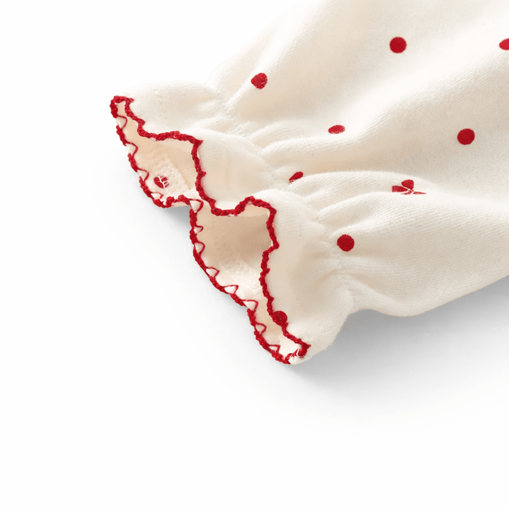 Zoom sur manche barboteuse bébé fille en coton doux avec volant et couture rouge décorative, combinaison confortable pour enfant 1 à 3 ans.