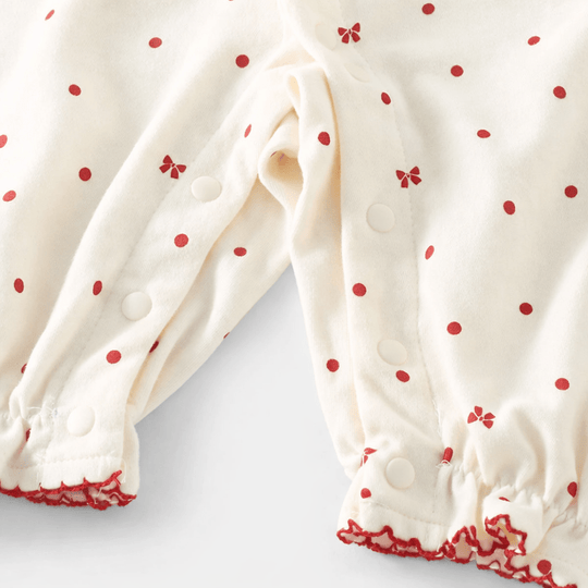 Zoom sur barboteuse bébé fille en coton doux à motif pois rouges, fermeture boutons pression pratique pour le change, vêtement enfant 1 à 3 ans.
