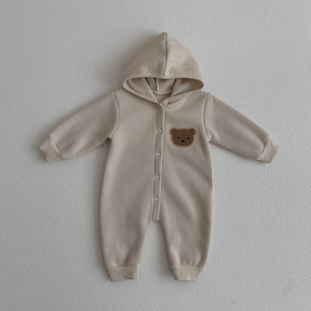 Combinaison bébé beige avec capuche et motif ourson sur la poitrine, vêtement doux et chaud.