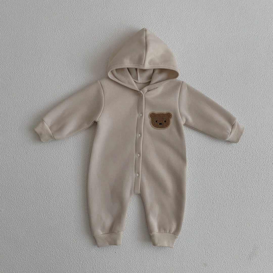 Combinaison bébé beige avec capuche et motif ourson sur la poitrine, vêtement doux et chaud.