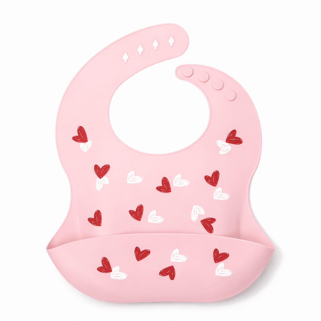 Bavoir bébé en silicone rose avec poche récupératrice, décoré de petits cœurs rouges et blancs, sur fond blanc