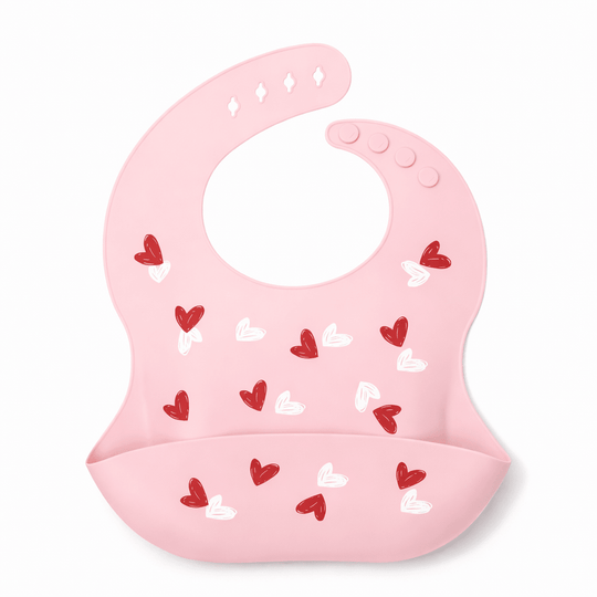 Bavoir bébé en silicone rose avec poche récupératrice, décoré de petits cœurs rouges et blancs, sur fond blanc