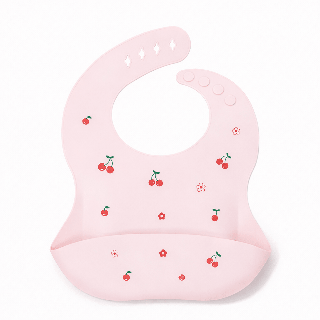 Bavoir bébé en silicone rose avec poche récupératrice, décoré de petites cerises rouges et fleurs, sur fond blanc