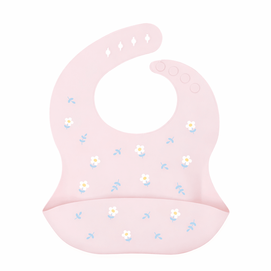 Bavoir bébé en silicone rose avec poche récupératrice, décoré de petites fleurs blanches et feuilles bleues, sur fond blanc