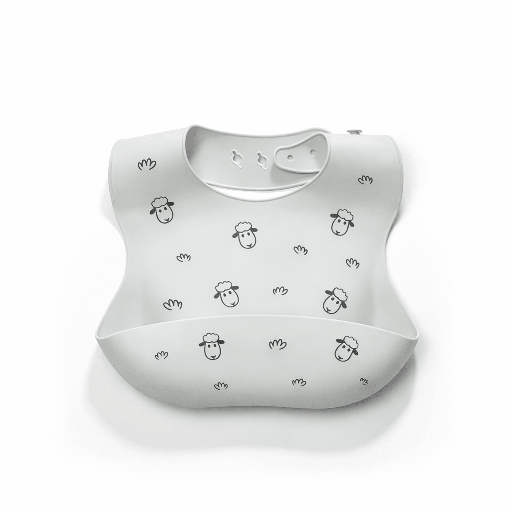 Bavoir bébé en silicone vert clair avec poche récupératrice, décoré de petits moutons noirs et motifs minimalistes, sur fond blanc

