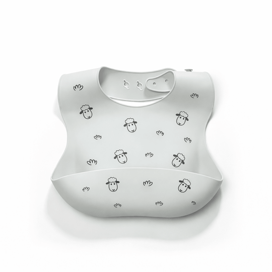 Bavoir bébé en silicone vert clair avec poche récupératrice, décoré de petits moutons noirs et motifs minimalistes, sur fond blanc
