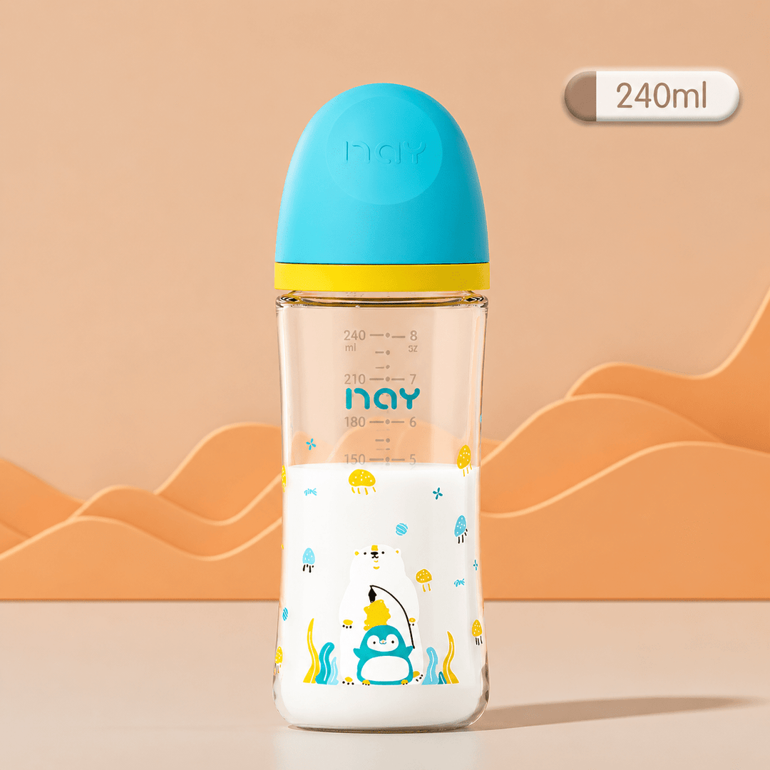 Biberon en verre pour bébé de 240 ml avec capuchon bleu turquoise et jaune, décoré d’un pingouin et d’un ours polaire. Biberon anti-colique transparent présenté sur un fond beige dans un style professionnel et épuré