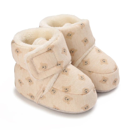 Bottines bébé crème décorées de multiples petites têtes d’ours brodées. Intérieur doux et chaud, fermeture ajustable et semelle flexible pour un confort optimal.