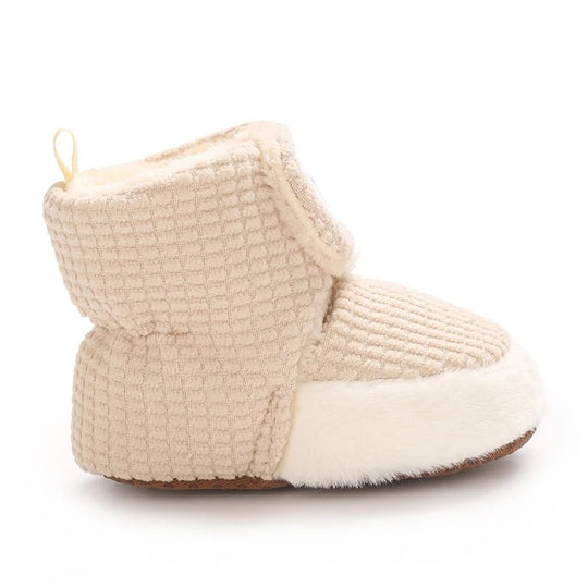 Modèle cocooning en maille gaufrée beige, doublure moelleuse et finition blanche en fausse fourrure. Parfait pour un confort maximal.