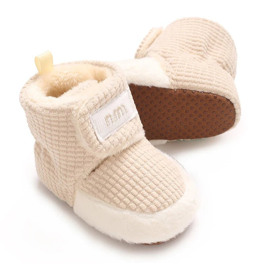 Bottines bébé en tissu gaufré ultra doux, intérieur chaud en fausse fourrure et fermeture velcro pratique. Semelle souple antidérapante pour un confort parfait à la maison comme en poussette.