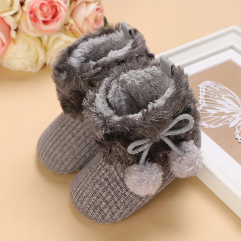 Bottines bébé grises avec fourrure gris foncé et pompons, modèle chaud et antidérapant.