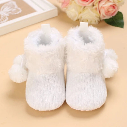 Bottines bébé blanc pur avec pompons et fourrure blanche, chaudes et douces pour l’hiver.