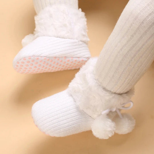 Bottines bébé blanches portées, semelle antidérapante à pois roses et fourrure douce.