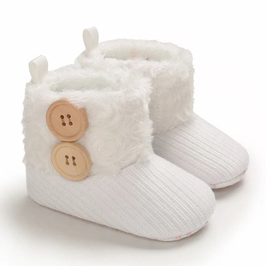 Bottines bébé blanc neige avec fourrure blanche et boutons en bois, style cocooning d’hiver.