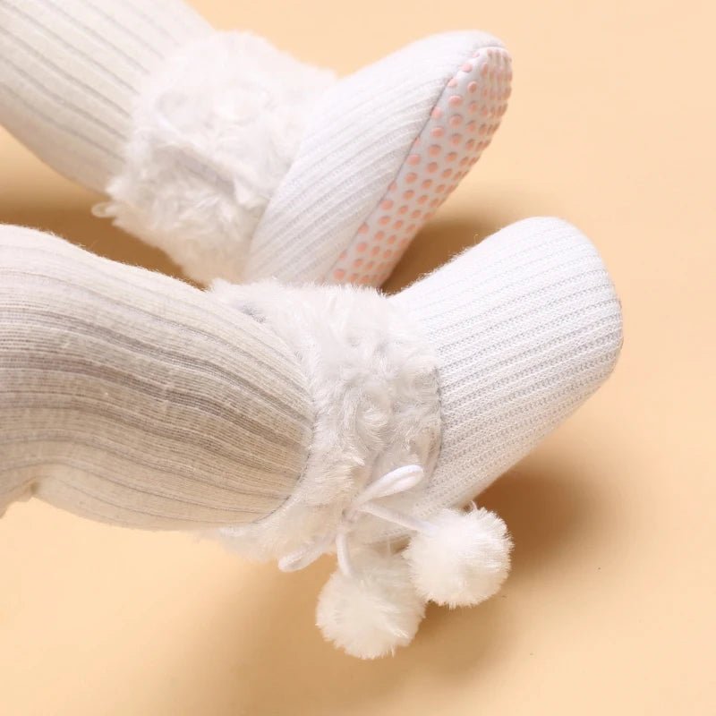 Bottines bébé blanches avec fourrure et pompons, semelle souple antidérapante.