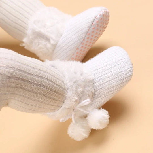 Bottines bébé blanches avec fourrure et pompons, semelle souple antidérapante.
