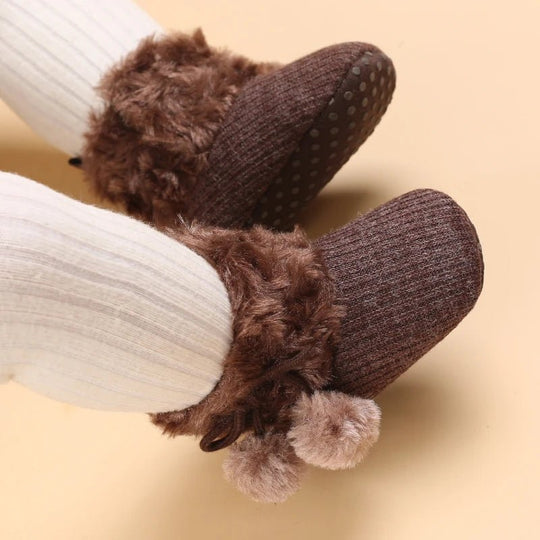 Bottines bébé brun noisette portées, semelle brune à pois antidérapants et fourrure douce.