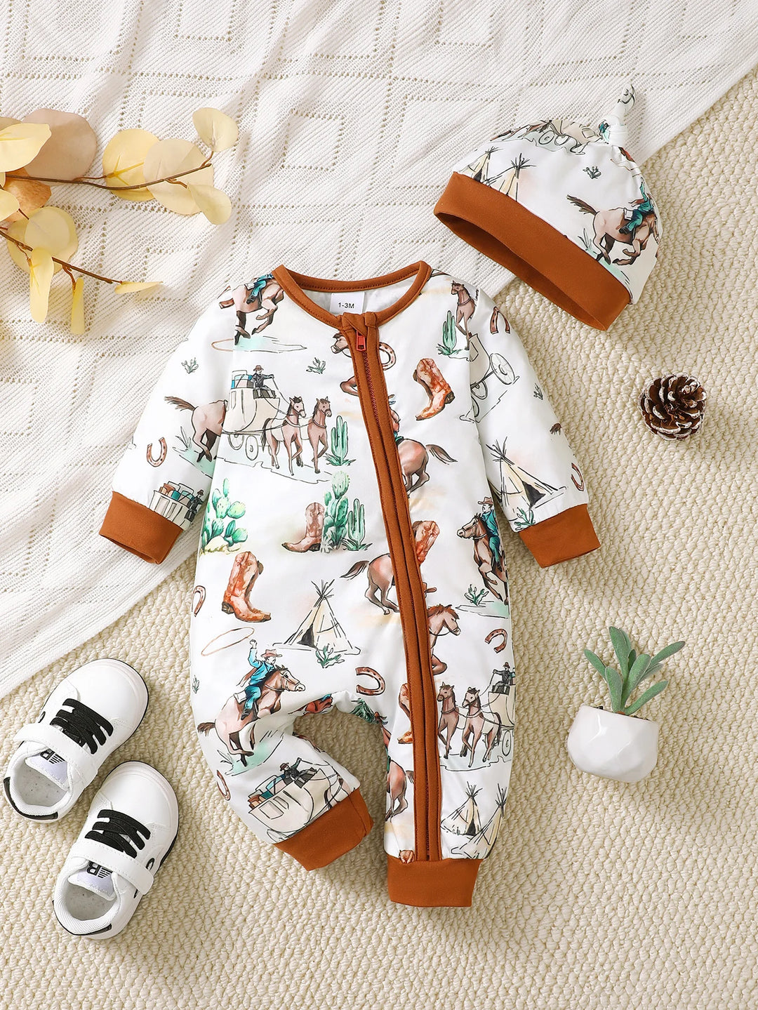 Combinaison bebe theme cowboy avec chevaux, bottes et chariot, bordures marron, avec bonnet assorti kalinatur.
