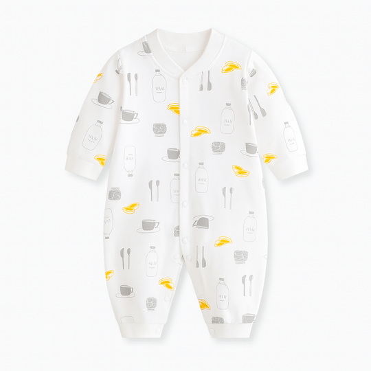 Combinaison bébé blanche décorée de motifs tasses, bouteilles de lait, cuillères et petits fruits jaunes, style gourmand et original.