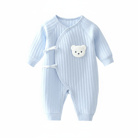 Combinaison bébé côtelée bleu pastel avec fermeture croisée et patch ourson blanc.