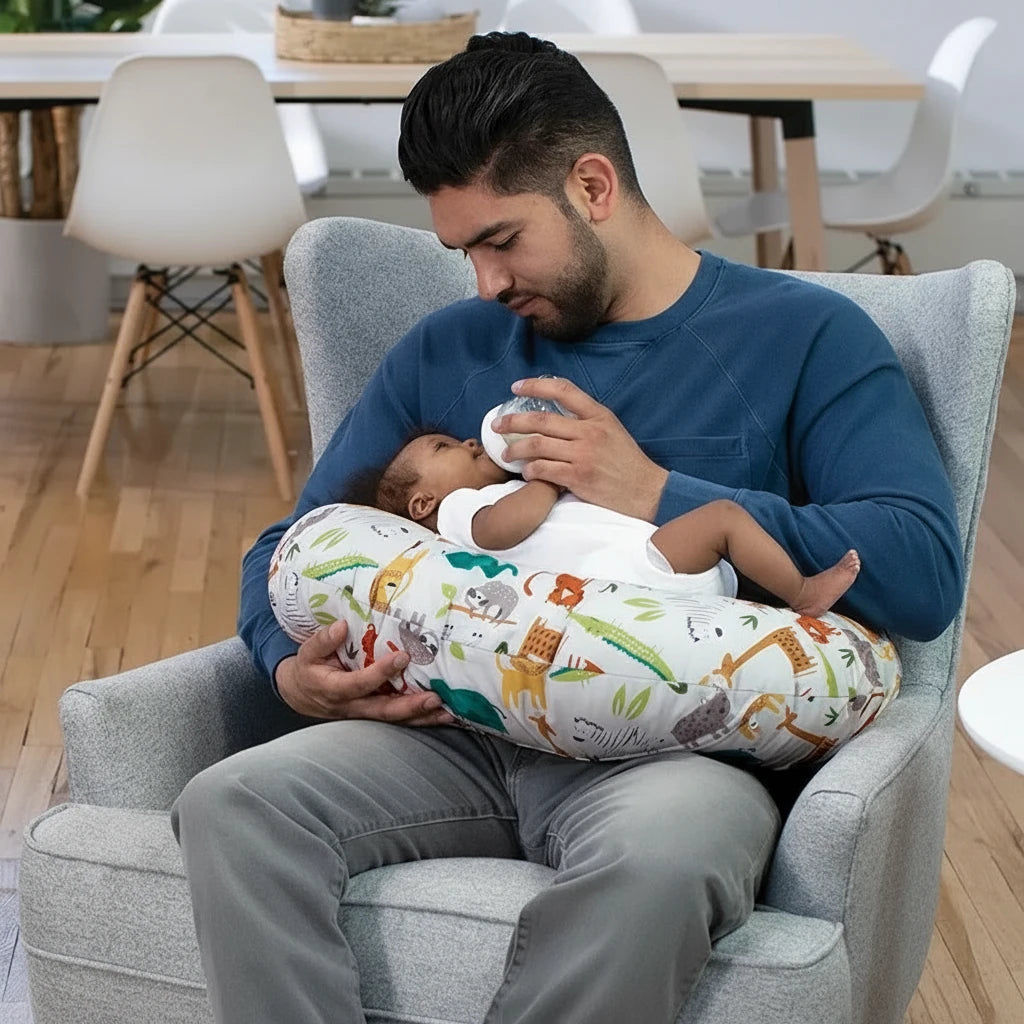 Papa nourrissant son bébé avec un biberon posé sur un coussin d’allaitement ergonomique à motifs jungle Kalinatur™, pour un confort optimal et un soutien doux.

