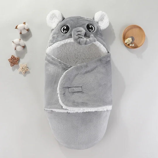 Couverture bébé grise en forme d’éléphant avec capuche et trompe 3D, intérieur blanc en tissu doux et chaud, accessoire cocooning Kalinatur idéal pour envelopper bébé.

