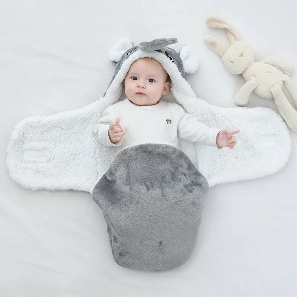 Bébé allongé dans une couverture grise en forme d’éléphant ouverte, intérieur blanc chaud et moelleux, design Kalinatur idéal pour garder bébé au chaud avec douceur et confort.
