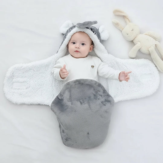 Bébé allongé dans une couverture grise en forme d’éléphant ouverte, intérieur blanc chaud et moelleux, design Kalinatur idéal pour garder bébé au chaud avec douceur et confort.

