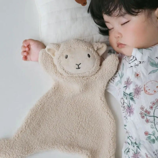 Bébé endormi avec un doudou agneau beige en bouclette douce