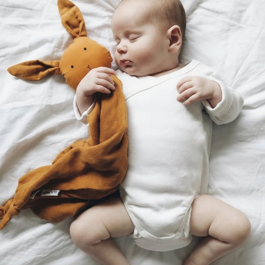Bébé dormant avec un doudou lapin en mousseline couleur moutarde – Kalinatur