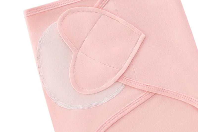 Gros plan sur la fermeture en forme de cœur du nid d’ange rose pour nouveau-né, montrant les coutures et la texture douce.