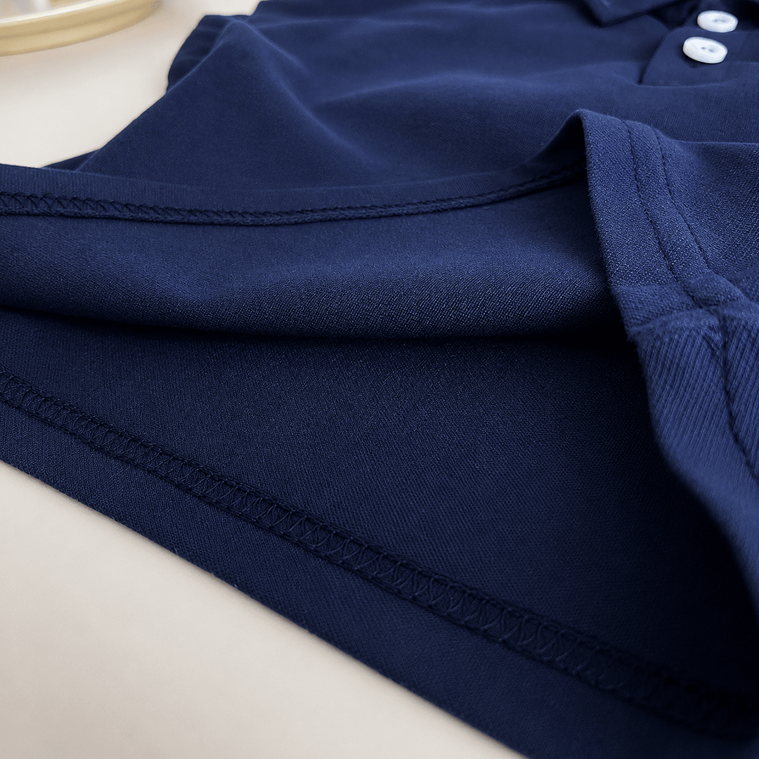 Gros plan sur le tissu bleu marine d’un polo bébé garçon montrant la qualité du textile, les coutures renforcées, les finitions soignées et le confort du vêtement pour une utilisation quotidienne.