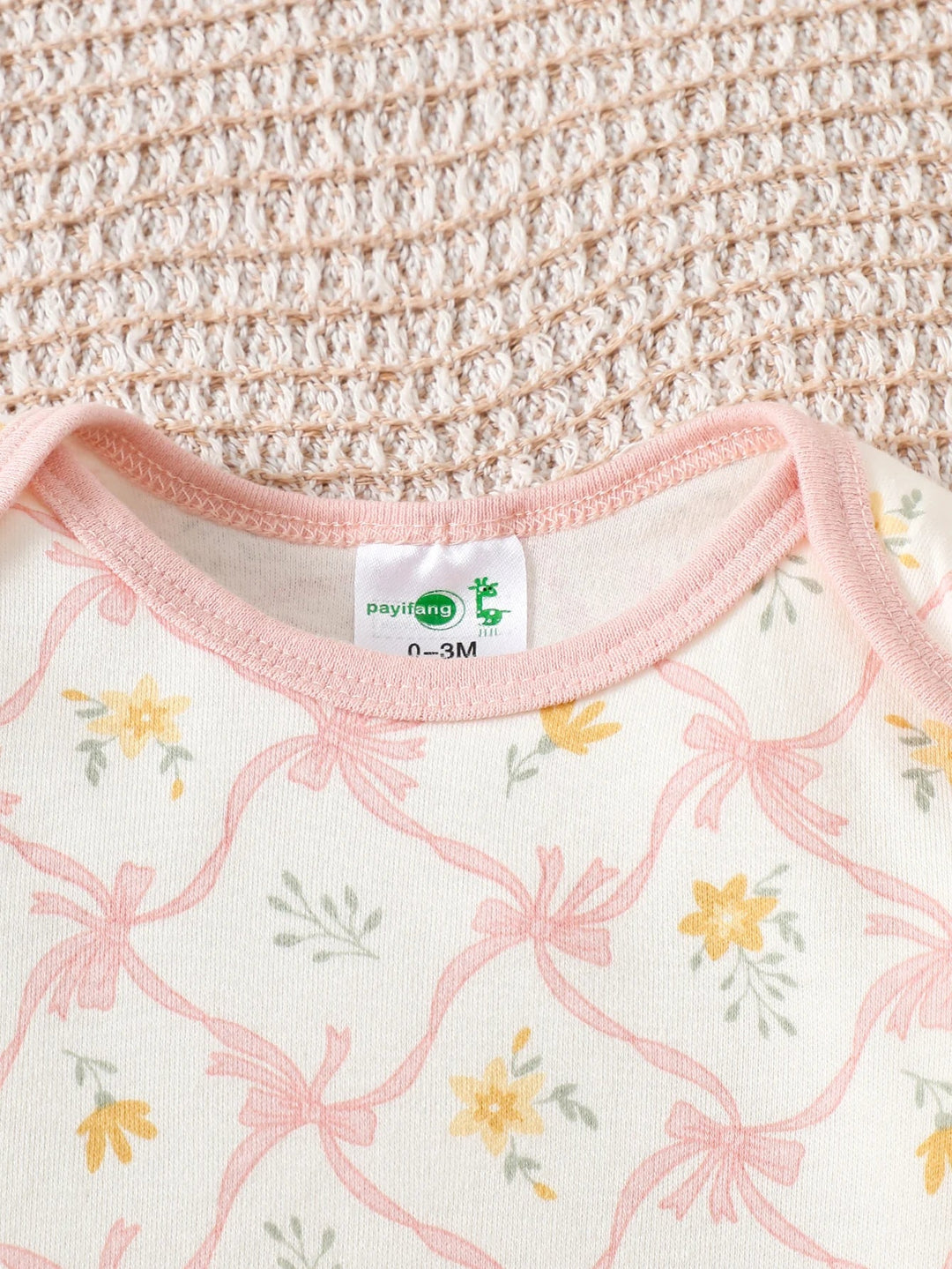 Détail du col d’un body bébé à motifs fleurs roses et jaunes, tissu doux et confortable Kalinatur.