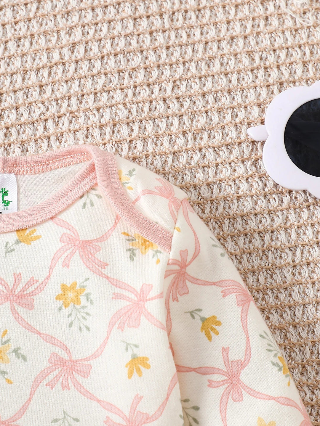 Détail des épaules d’un body bébé à motifs fleurs roses et jaunes, finition douce et confortable Kalinatur.