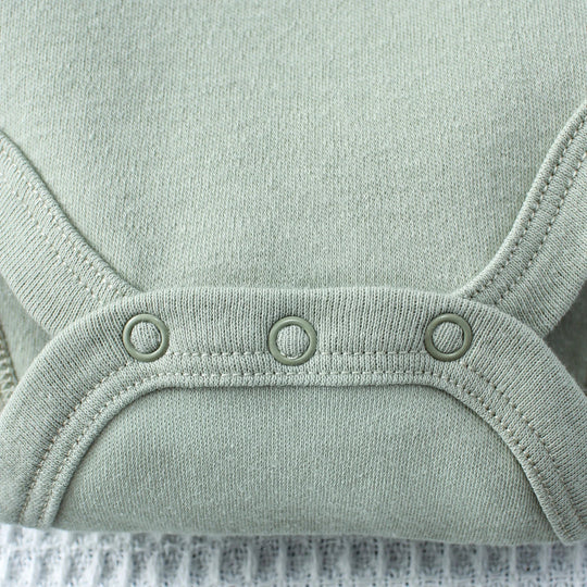 Gros plan sur les boutons-pression du body bébé en coton, finition solide et pratique – collection Kalinatur