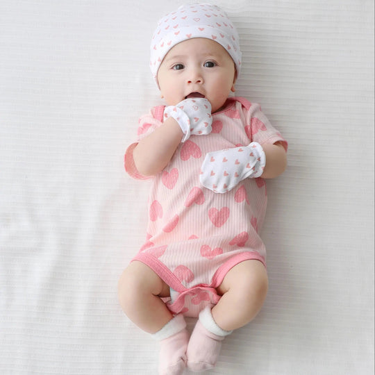 Bébé portant un body rose à cœurs avec bonnet et moufles assortis, tenue douce et confortable Kalinatur.