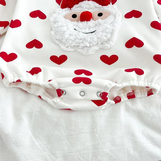 Détail du body bébé blanc Kalinatur avec imprimé de cœurs rouges, motif Père Noël en relief et boutons-pression à l’entrejambe.