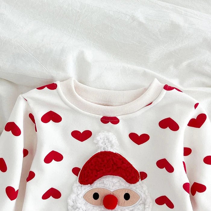 Détail du body bébé blanc Kalinatur avec imprimé cœurs rouges et motif Père Noël en relief au niveau de la poitrine.