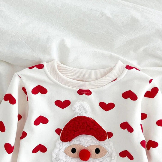 Détail du body bébé blanc Kalinatur avec imprimé cœurs rouges et motif Père Noël en relief au niveau de la poitrine.