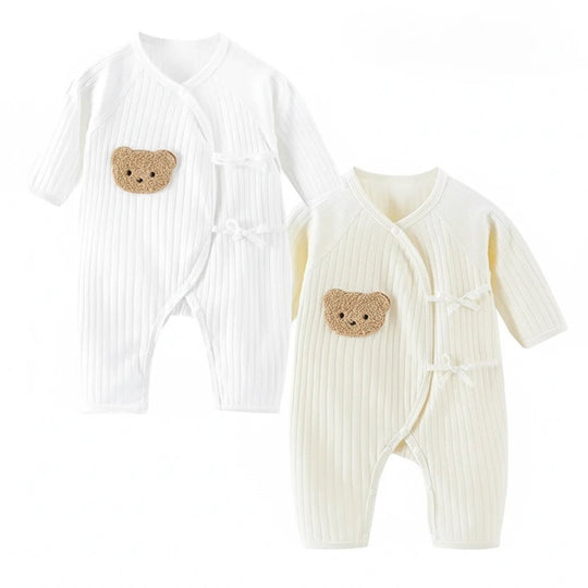 Combinaison bébé blanche côtelée avec fermeture croisée et patch ourson brodé sur le côté.