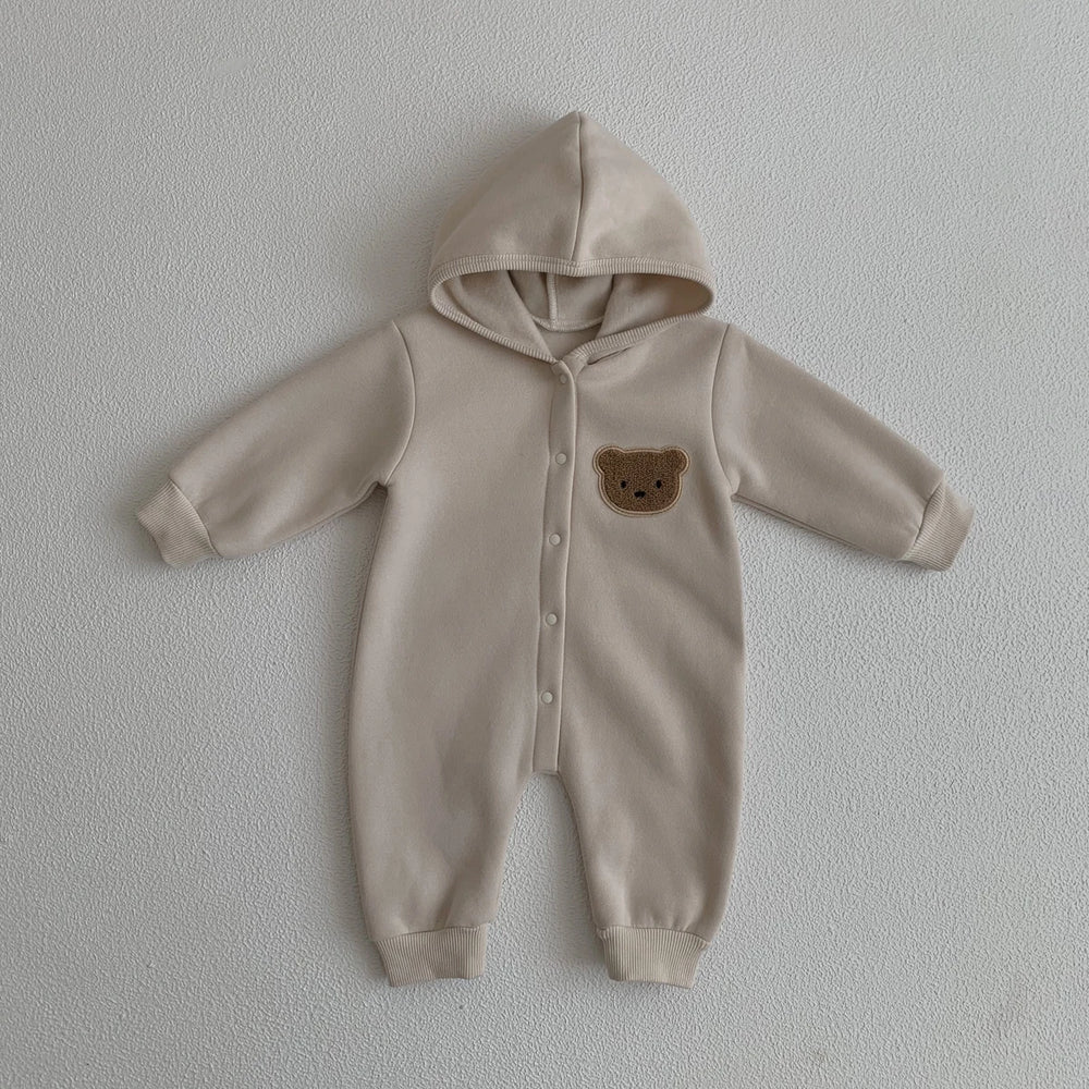Combinaison bébé beige avec capuche et motif ourson sur la poitrine, vêtement doux et chaud.