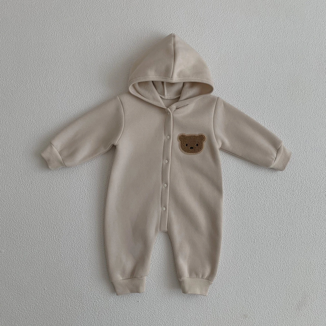 Combinaison bébé beige avec capuche et motif ourson sur la poitrine, vêtement doux et chaud.