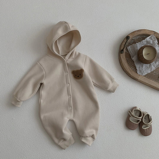 Combinaison bébé beige à capuche avec patch ourson, présentée avec des chaussons assortis.