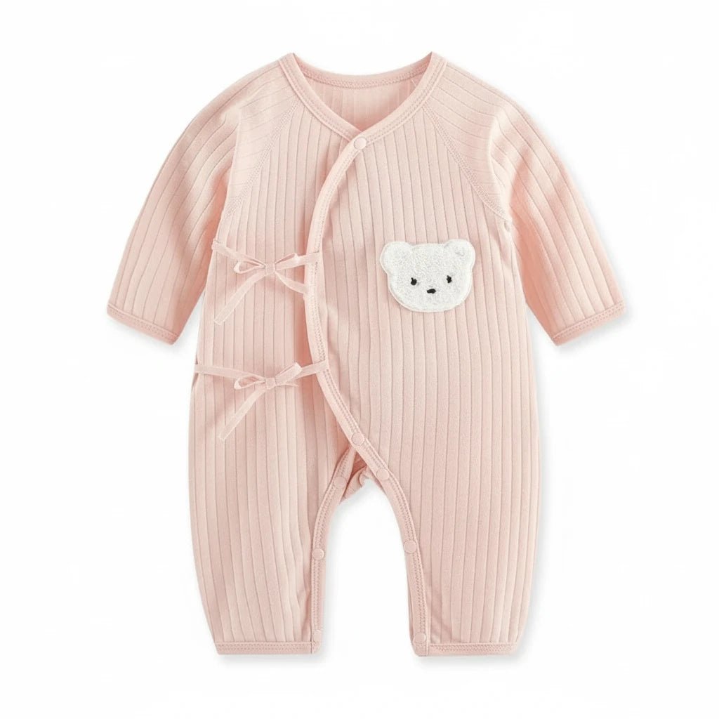Combinaison bébé rose poudré côtelée avec fermeture croisée et patch ourson blanc.